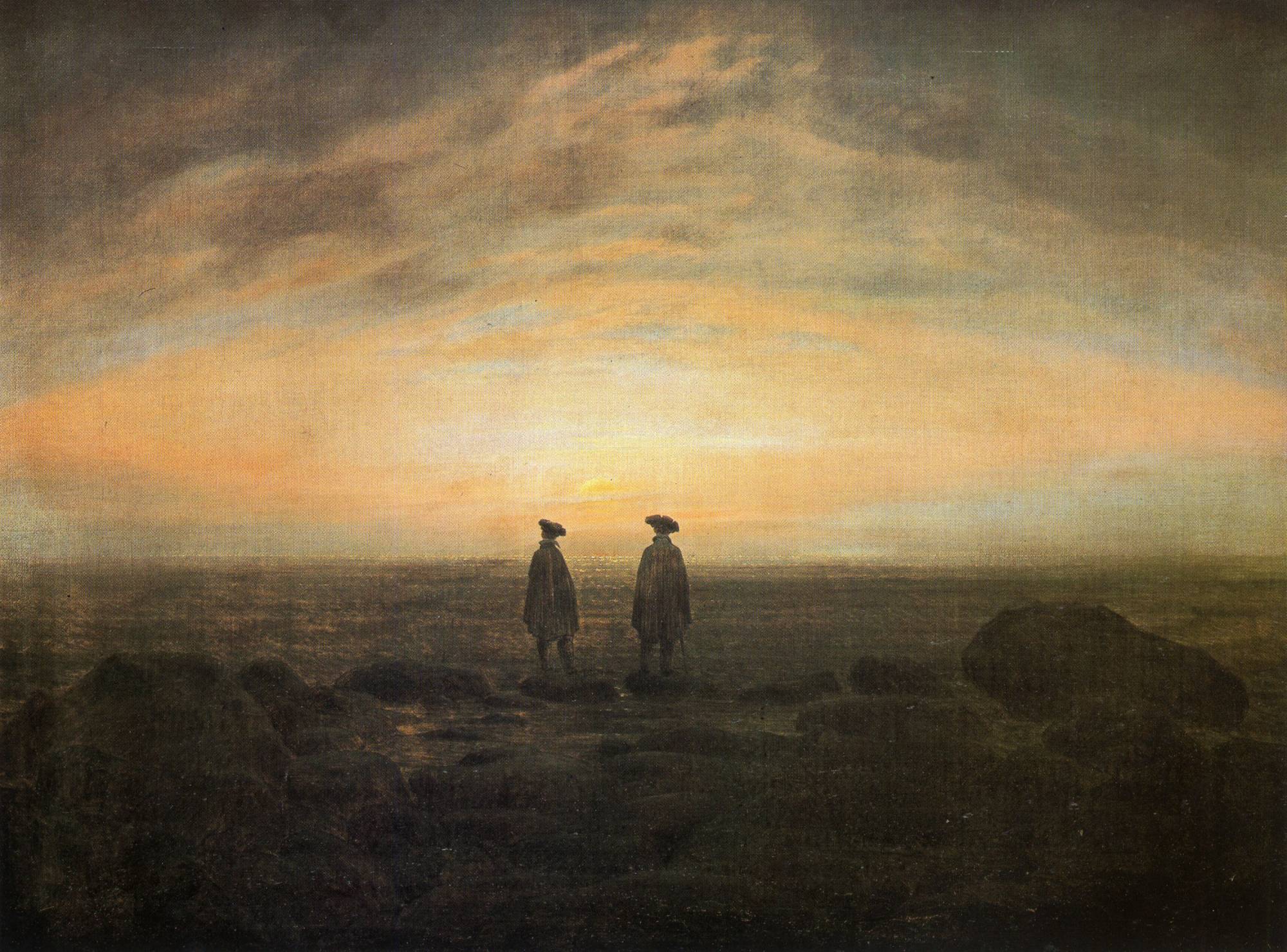 Two cloaked men seen from behind, standing on a rocky shore and looking out over the sea at a glowing horizon.